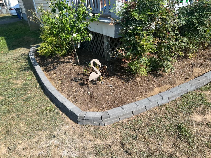 Curved paver-block edging along a shrub bed under a deck